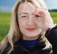 Frau formt Finger zu einem Gucklock und schaut durch
